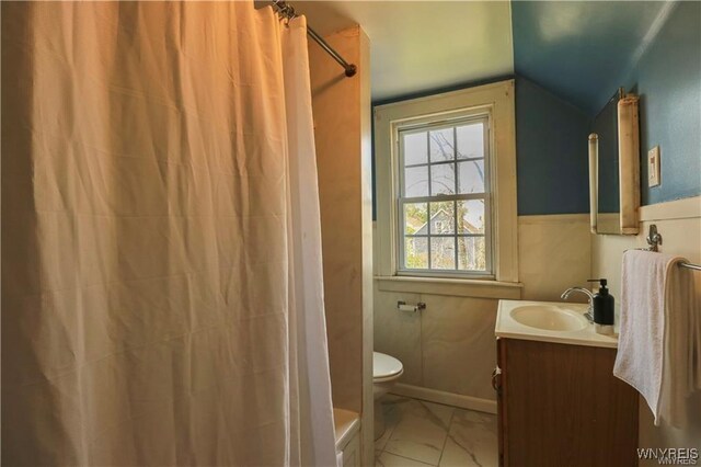 full bathroom featuring toilet, marble finish floor, vaulted ceiling, and vanity