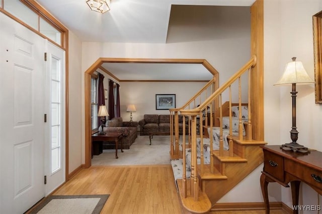 foyer with arched walkways, stairway, and wood finished floors