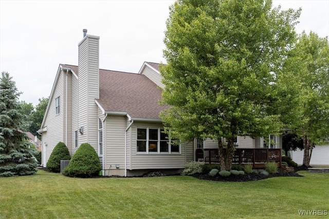 rear view of house featuring a lawn, a chimney, roof with shingles, cooling unit, and a wooden deck