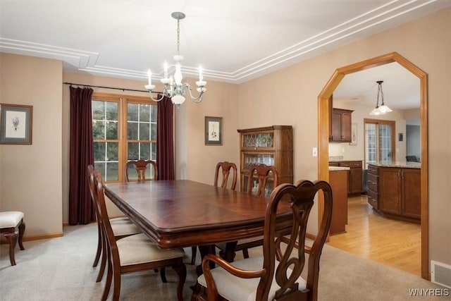 dining area featuring a chandelier, light colored carpet, visible vents, and baseboards