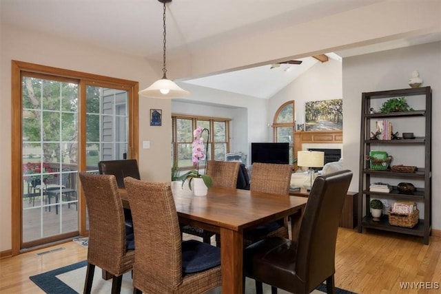 dining room featuring light wood-style floors, a wealth of natural light, visible vents, and vaulted ceiling