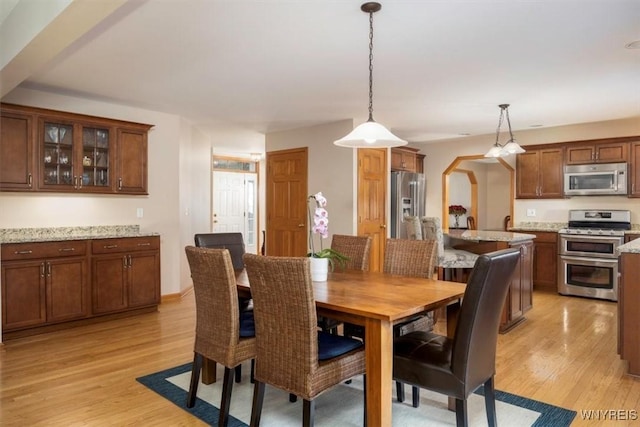 dining area with arched walkways and light wood-style floors