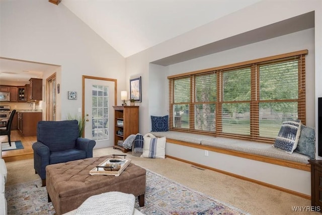 living area with carpet floors, baseboards, and high vaulted ceiling