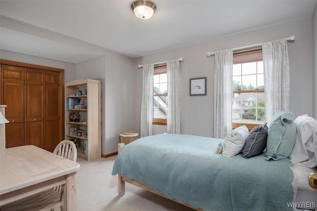 bedroom with light colored carpet and baseboards