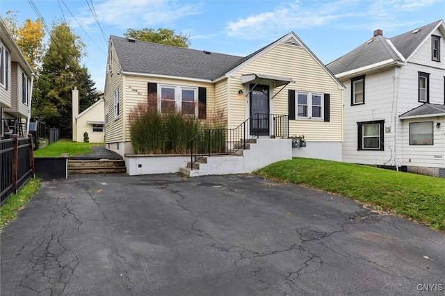 view of front of home featuring a front lawn, roof with shingles, and fence