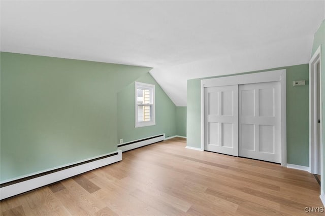 bonus room with a baseboard radiator, light wood-style flooring, baseboard heating, vaulted ceiling, and baseboards