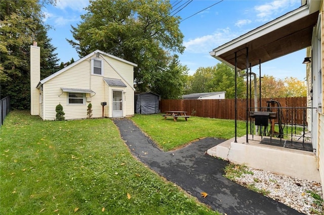 exterior space featuring a fenced backyard, an outdoor structure, a patio, and a storage unit