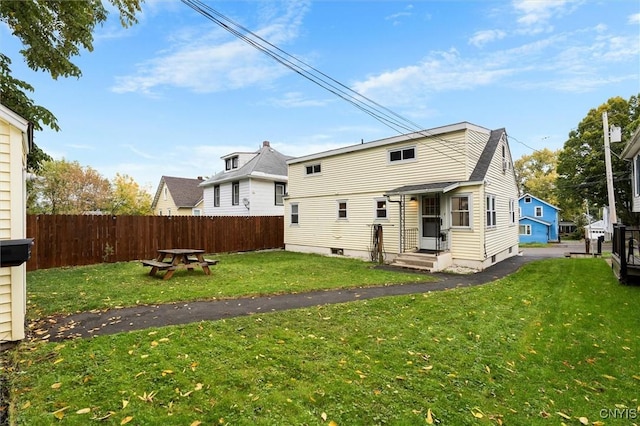 rear view of property with a lawn and fence