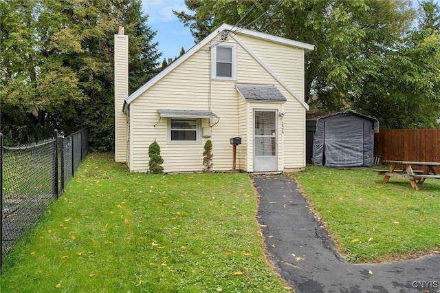 view of front facade featuring a front lawn, a chimney, and a fenced backyard