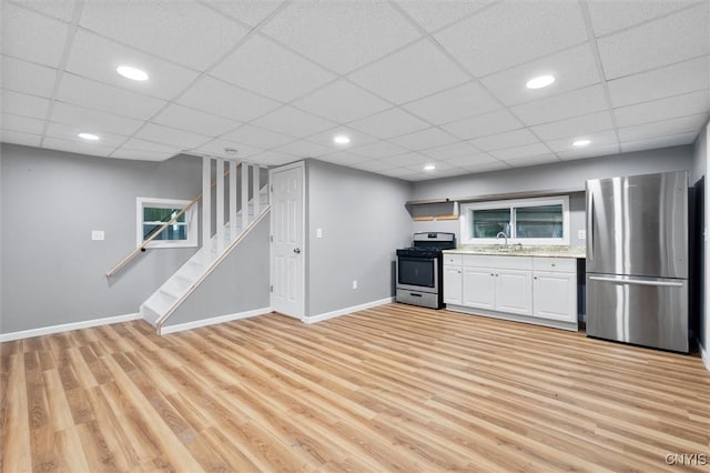 kitchen featuring stainless steel appliances, light wood-type flooring, a sink, and baseboards