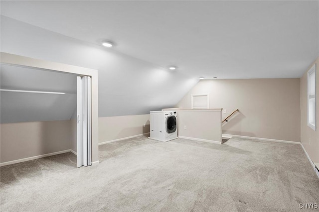 interior space with lofted ceiling, washer / dryer, carpet, and baseboards