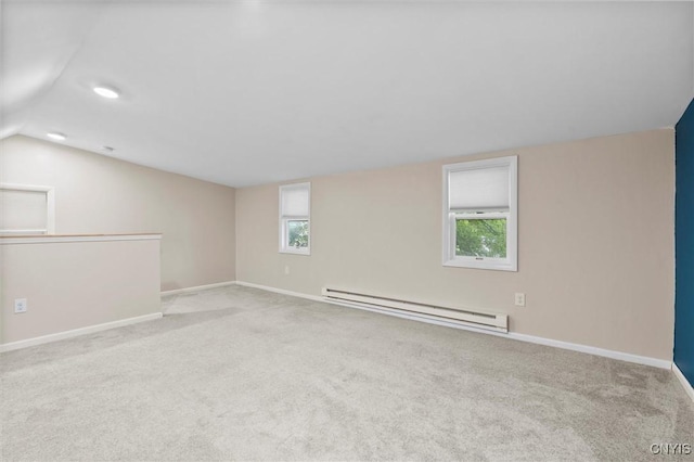 carpeted empty room with a baseboard radiator, a healthy amount of sunlight, vaulted ceiling, and baseboards