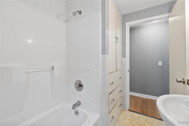 bathroom with shower / bath combination, baseboards, and a sink