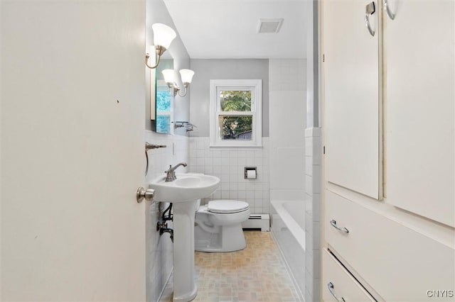 full bathroom with tile walls, visible vents, toilet, a baseboard heating unit, and a sink