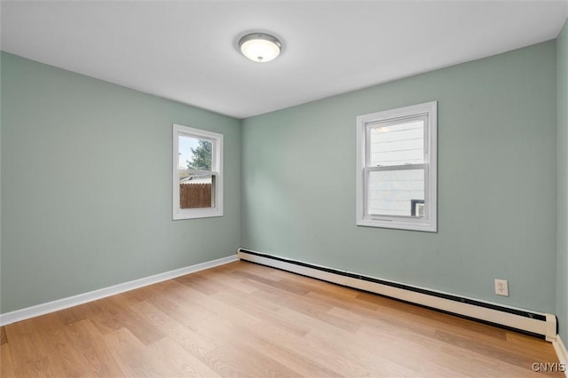 empty room with a baseboard radiator, baseboards, and wood finished floors