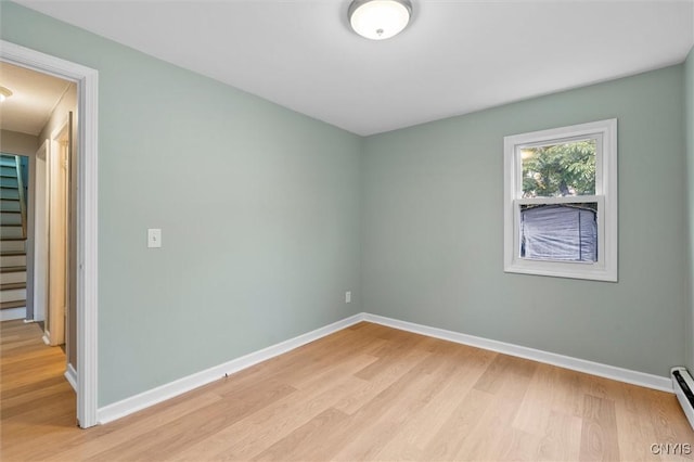 empty room featuring light wood-type flooring, baseboards, and stairs