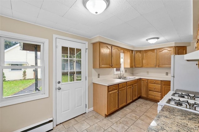 kitchen with white appliances, a baseboard radiator, brown cabinets, light countertops, and a sink