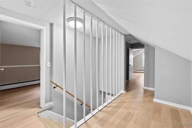 corridor featuring baseboards, a baseboard heating unit, vaulted ceiling, and wood finished floors