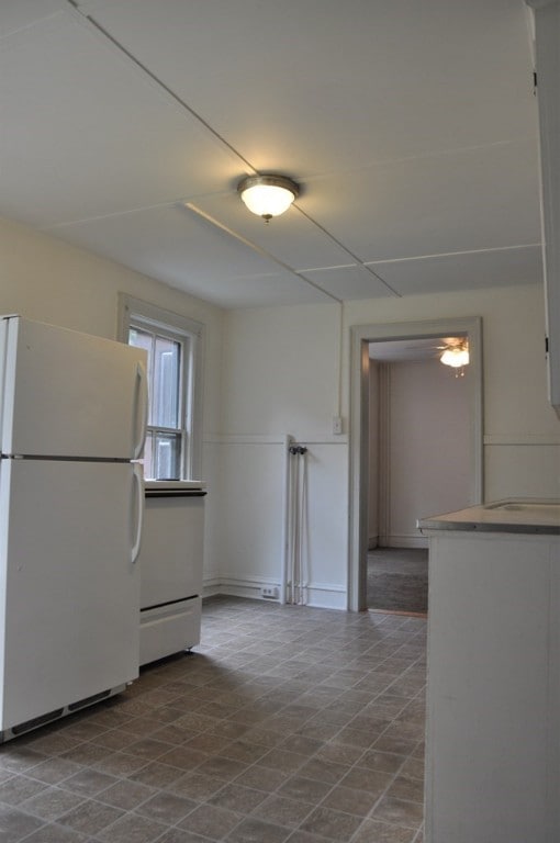 kitchen featuring freestanding refrigerator and white cabinets