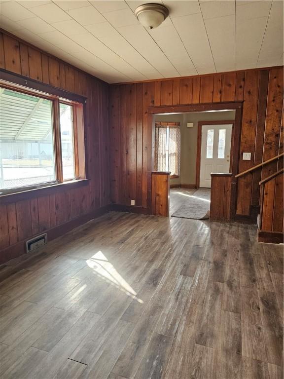 spare room with wood walls, visible vents, and dark wood-type flooring