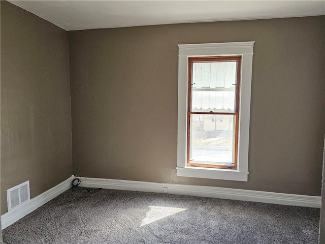 carpeted empty room featuring baseboards and visible vents