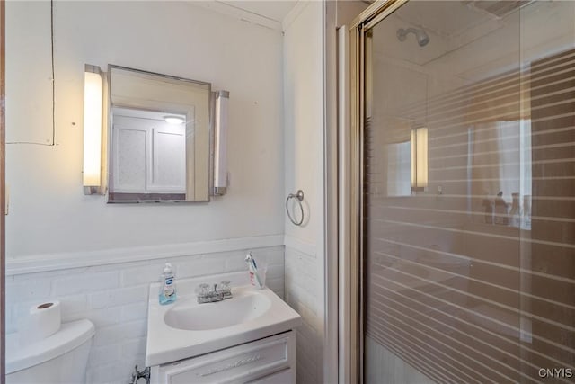 full bath featuring toilet, a stall shower, vanity, and wainscoting