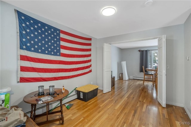 interior space featuring a baseboard heating unit, wood finished floors, and baseboards