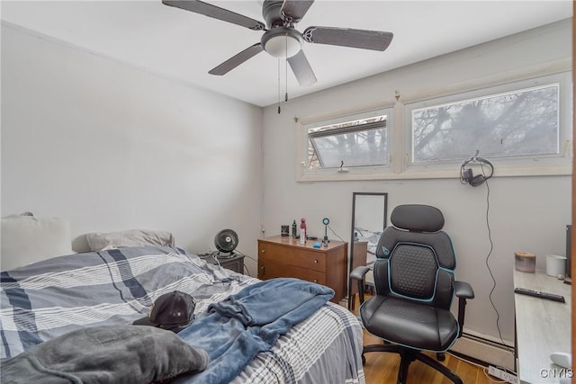 bedroom featuring a baseboard heating unit, ceiling fan, and wood finished floors