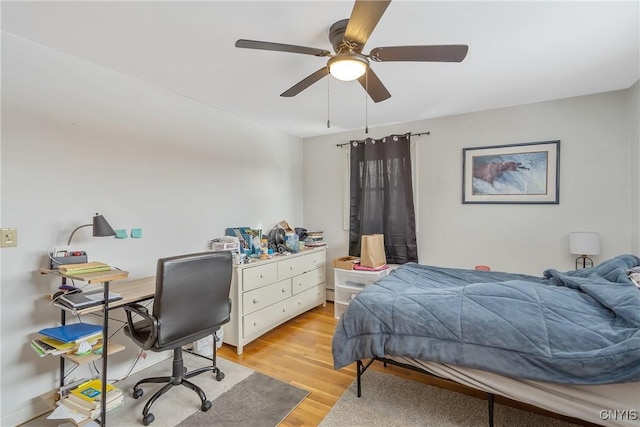 bedroom with ceiling fan, a baseboard heating unit, and light wood-type flooring