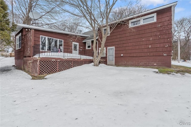 snow covered back of property featuring a wooden deck