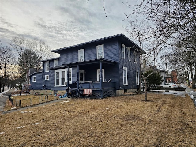 view of front of house with a porch, a front yard, and fence