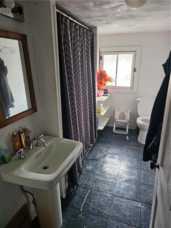 bathroom with a shower with shower curtain and toilet