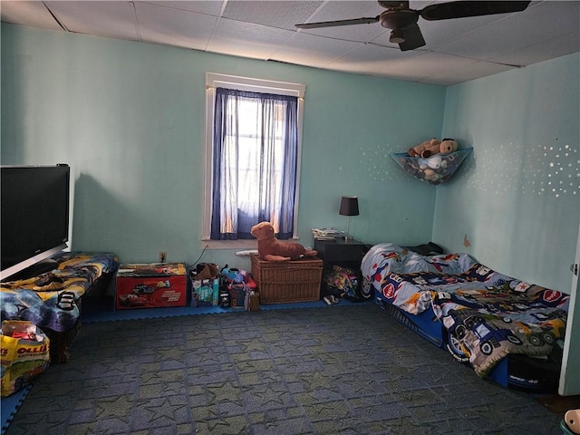 carpeted bedroom with ceiling fan and a paneled ceiling