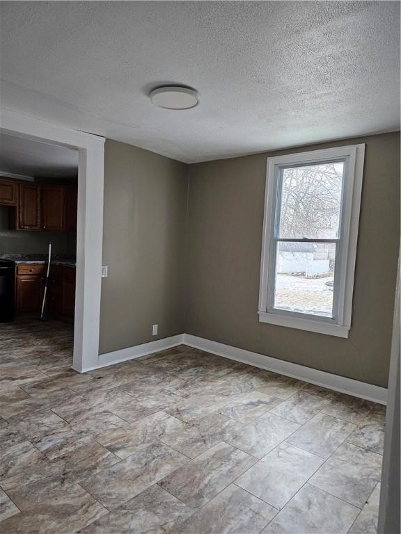 unfurnished room featuring a textured ceiling and baseboards