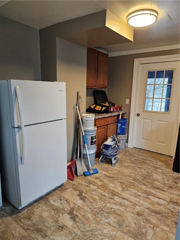 kitchen featuring light countertops, freestanding refrigerator, and brown cabinets