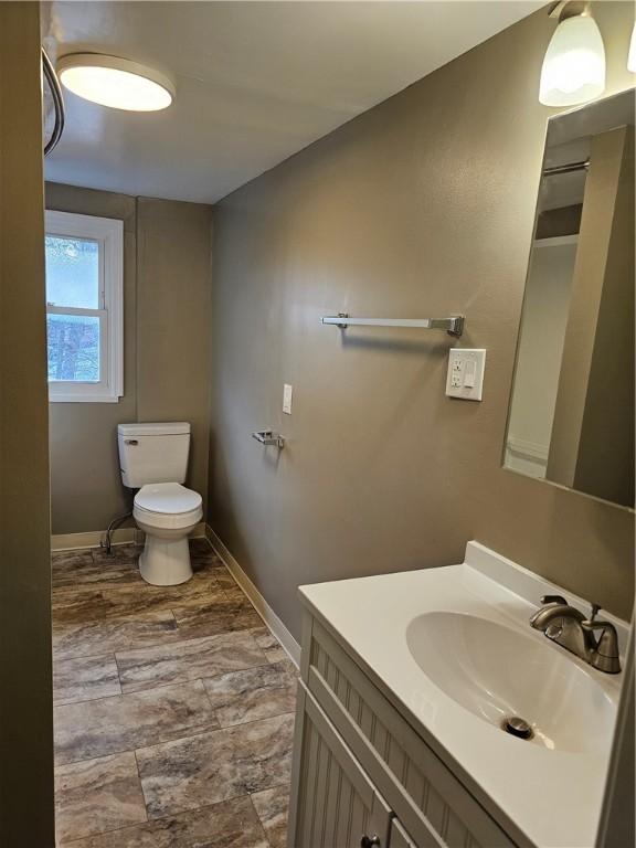 bathroom featuring baseboards, vanity, and toilet