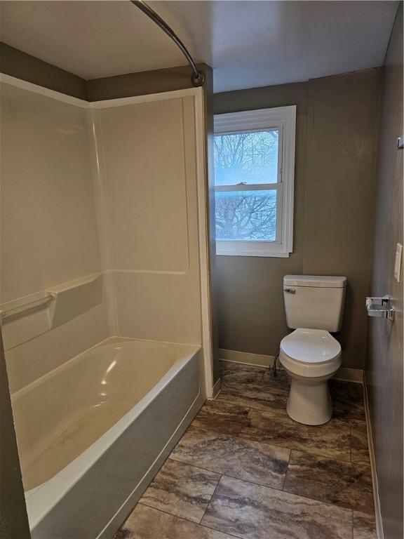 bathroom featuring shower / bath combination, baseboards, and toilet