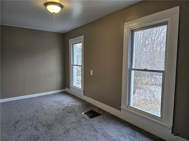 carpeted spare room with visible vents and baseboards