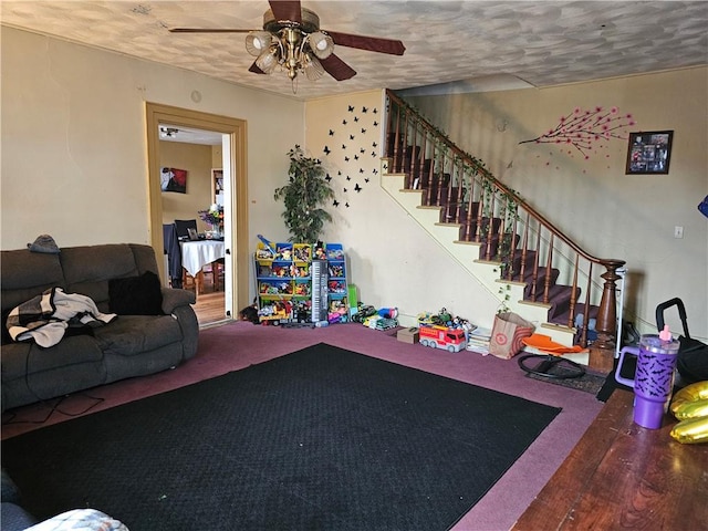 living room featuring a ceiling fan, a textured ceiling, stairway, and carpet flooring