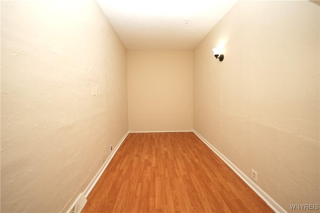 hall featuring visible vents, baseboards, and wood finished floors