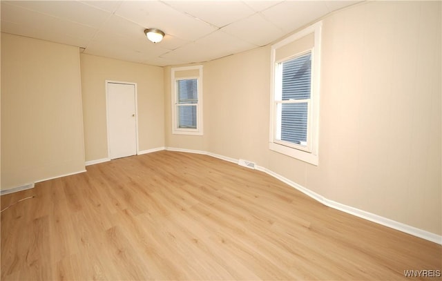 spare room featuring visible vents, a drop ceiling, light wood-style flooring, and baseboards