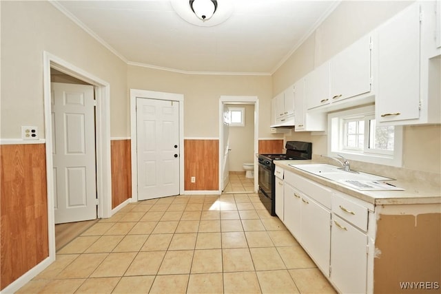 kitchen with crown molding, light countertops, wainscoting, black range with gas cooktop, and under cabinet range hood