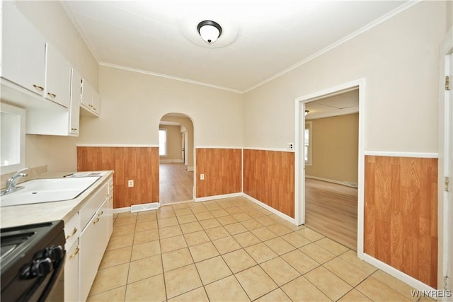 kitchen featuring a wainscoted wall, black range with gas cooktop, arched walkways, and a sink