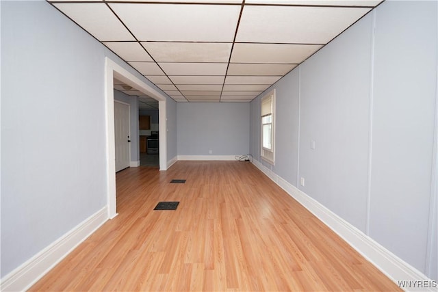 spare room featuring light wood-style floors, a paneled ceiling, visible vents, and baseboards