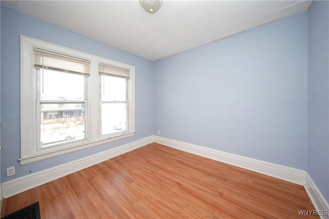 spare room with light wood-style flooring, visible vents, and baseboards