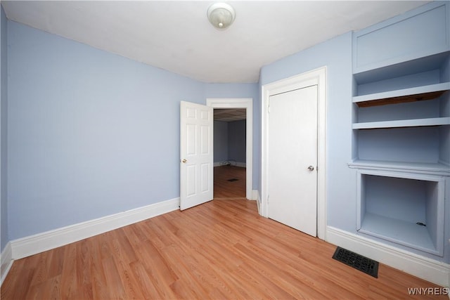 unfurnished bedroom with light wood-type flooring, baseboards, visible vents, and a closet