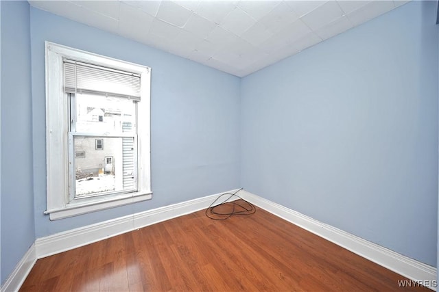 spare room featuring baseboards and wood finished floors