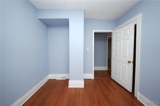 unfurnished bedroom featuring wood finished floors, visible vents, and baseboards