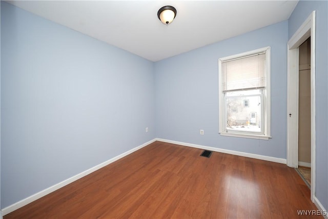 unfurnished bedroom with wood finished floors, visible vents, and baseboards