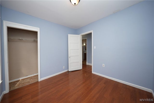 unfurnished bedroom featuring a closet, baseboards, and wood finished floors